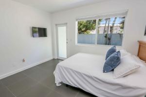 a white bedroom with a bed with pillows and a window at Mimo Bungalows By Renzzi in Miami +25 photos
