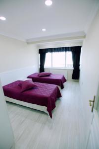 トラブゾンにあるBayramoglu Airport Apartの紫のシーツと窓が備わるベッドルームのベッド2台
