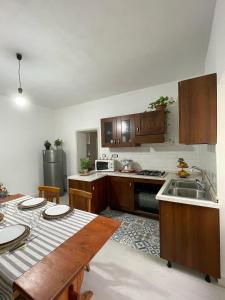 a kitchen with wooden cabinets and a table and a sink at La casa di Nenni in Santa Giusta