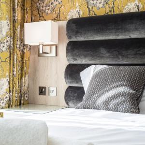 Schlafzimmer mit einem Bett mit einem schwarzen Kopfteil und einer Lampe in der Unterkunft The Residence Hotel at The Nottinghamshire Golf & Country Club in Nottingham