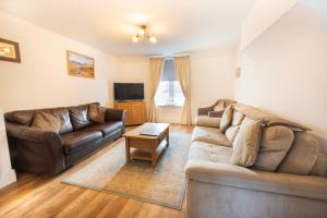 a living room with two couches and a tv at Cosy Llandudno Apartments in Llandudno