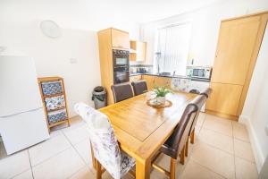 a kitchen and dining room with a wooden table and chairs at Cosy Llandudno Apartments in Llandudno