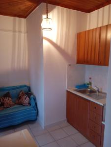 a kitchen with a blue couch and a sink at Mylonas Rooms in Pandokrátor +5 photos