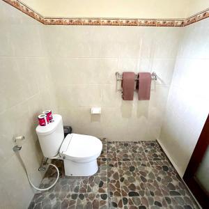 a bathroom with a toilet and towels on the wall at Dodit House in Ubud