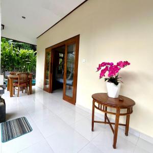a vase of flowers on a table in a living room at Dodit House in Ubud