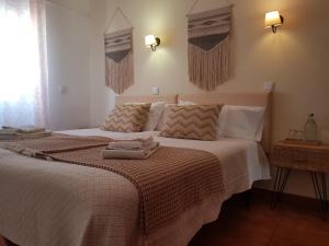 een slaapkamer met een groot bed met handdoeken erop bij Quartos Abelha in Porto Covo