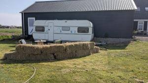 a trailer parked next to a house with hay at Gerestylde vintage caravan "Zee" met luxe badkamer bij "de Kapitein" in 't Horntje
