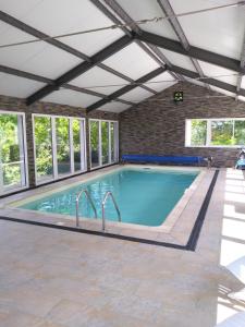 an indoor swimming pool with a ceiling and windows at Le champ bourdon in Saint-Maur-des-Bois