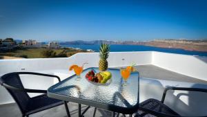 a table with a bowl of fruit and drinks on a balcony at Pancratium Villas & Suites in Akrotiri