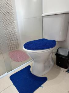 a bathroom with a toilet with a blue rug at Kitão Frente Mar Na Tupi! in Samaritá +19 photos
