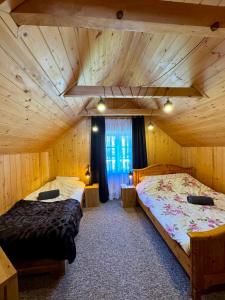 two beds in a room with wooden walls at Miejsce w lesie in Stara Huta