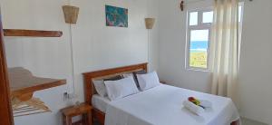 a bedroom with a bed with white sheets and a window at La Residence Emmaüs in Rodrigues Island
