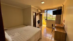 a bedroom with a bed and a window and a television at Hotel Carreiro Inhapim in Inhapim