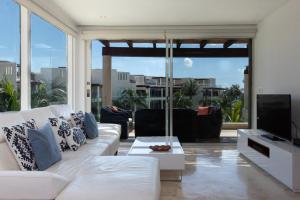 プラヤ・デル・カルメンにあるThe Elements Oceanfront & Beachside Condo Hotelのリビングルーム(白いソファ、テレビ付)