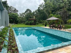 a swimming pool in a yard with a table and an umbrella at Residência Executiva de Alto Padrão - COP30 in Benevides