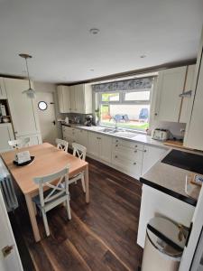 eine Küche mit Holztisch und Holzboden in der Unterkunft Molly's Cottage in Glenariff