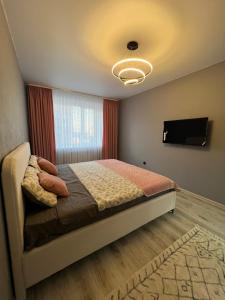 a bedroom with a bed and a flat screen tv at Kakdoma Apartments in Kostanay +4 photos