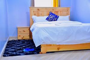 a bedroom with a wooden bed with a blue wall at WoodLands House in Naivasha