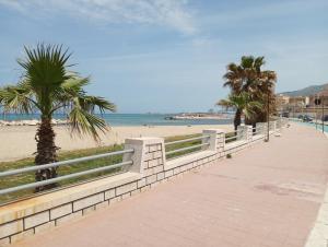 a sidewalk next to a beach with palm trees at Fardella 75 in Trapani