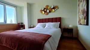 a bedroom with a large bed with a red headboard at Amorosa Beach Apartment Sea View in Viana do Castelo