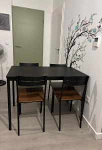 a black dining room table with two chairs and a vase at Villejuif - Métro Léo Lagrange - 2 pièces avec balcon in Villejuif
