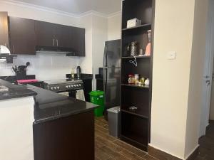 a kitchen with black cabinets and a black refrigerator at Family friendly apartment in Nairobi