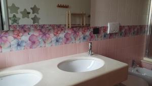 ein Badezimmer mit zwei Waschbecken und einer rosa Blumentapete in der Unterkunft La Bouganville in Mola di Bari + 30 Fotos