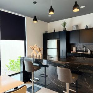 a kitchen with a large black counter and chairs at Casa Ru-Hè Mèrida in Mérida