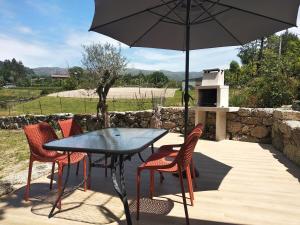 a patio with a table and chairs and an umbrella at Casa do Oitão in Vieira do Minho