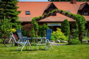 two chairs and a table in front of a house at Gościniec Zapiecek in Krutyński Piecek
