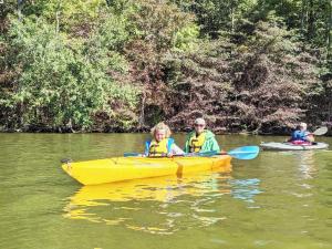 a man and two children in a yellow kayak on a river at Family Lake House Waterfront in Saugerties