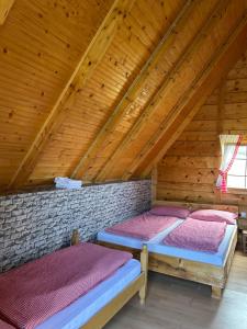 two beds in a attic room with wooden ceilings at Smaka Brvnare in Sjenica