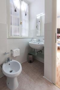 a white bathroom with a sink and a toilet at Hotel Villa Erica in Grado