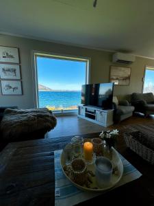 a living room with a television and a table with a candle at Sjønært feriehus, båt tilgjengelig for leie in Ålesund