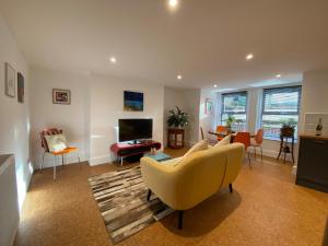 ein Wohnzimmer mit einem gelben Sofa und einem Fernseher in der Unterkunft Spacious Double Apartment in Folkestone with parking in Folkestone