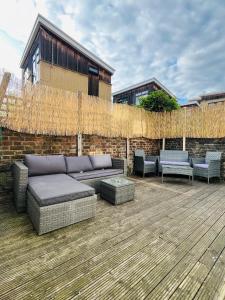 a patio with a couch and chairs on a wooden deck at Stylish 2-Bed Garden Flat, 5 Mins to Brixton in London