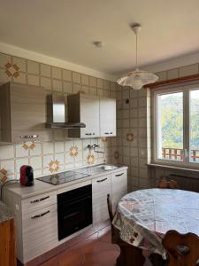 a kitchen with white cabinets and a table in it at Gold Cave casa vacanze relax nel bosco appartamenti in Pessinetto +30 photos