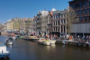 a group of boats docked in a river with buildings at Hotel Aadam Wilhelmina in Amsterdam +18 photos