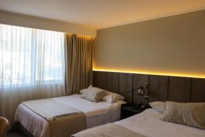 Una habitación de hotel con dos camas y una ventana. en Hotel Terrano Concepción, en Concepción