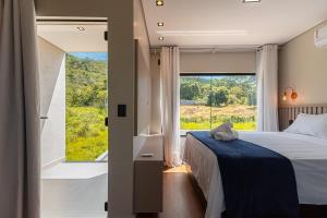 a bedroom with a bed and a large window at Linda casa no condomínio Piri Living in Pirenópolis