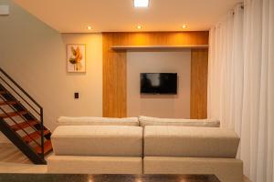 a living room with a couch and a flat screen tv at Linda casa no condomínio Piri Living in Pirenópolis