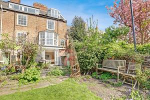 a garden in front of a brick house with a bench at Martineau House - North East Escapes in Tynemouth