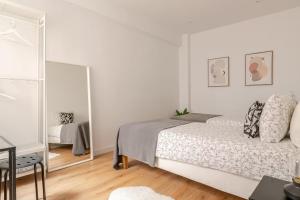 a white bedroom with a bed and a mirror at Habitación privada en el centro de Bilbao in Bilbao