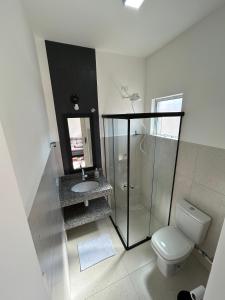 a white bathroom with a toilet and a sink at Casa da Vila in Monte Alegre do Sul