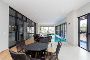 ein Esszimmer mit Tischen, Stühlen und einem Pool in der Unterkunft Apartamentos para 5 pessoas com Piscina e Academia no Centro in Curitiba
