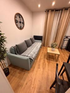 salon z kanapą i zegarem na ścianie w obiekcie F2 moderne proche Paris w mieście Alfortville