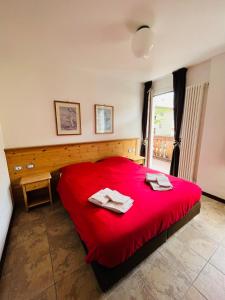 una camera da letto con un letto rosso con due asciugamani sopra di Dolomia Home Bormio a Bormio