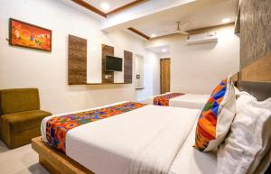 Una habitación de hotel con dos camas y una silla. en Hotel Silverkey International - Olive, en Mathura