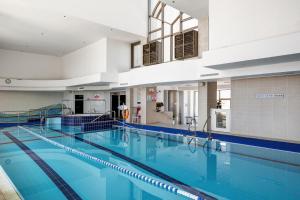 a large swimming pool with blue water in a building at A white dream by the sea - 2bd lux family apartment in Herzliyya B