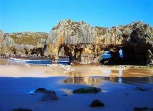 a beach with a cave and a rock formation at Llanesmar in Posada de Llanes